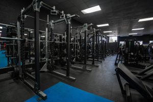 Row of squat racks with barbells and weight plates in the strength training area at Halo Gym