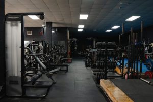 Halo Gym floor featuring strength machines, free weights, and a wooden-and-rubber deadlift platform with barbells and weight plates.